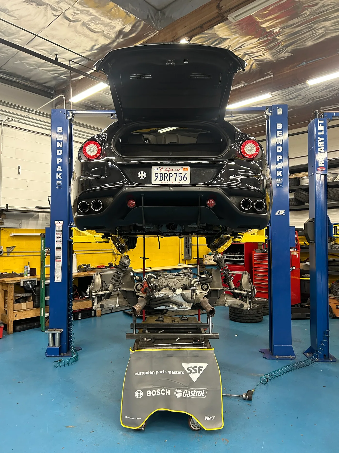 Underside of a car raised on a two-post lift showing the exhaust and rear subframe